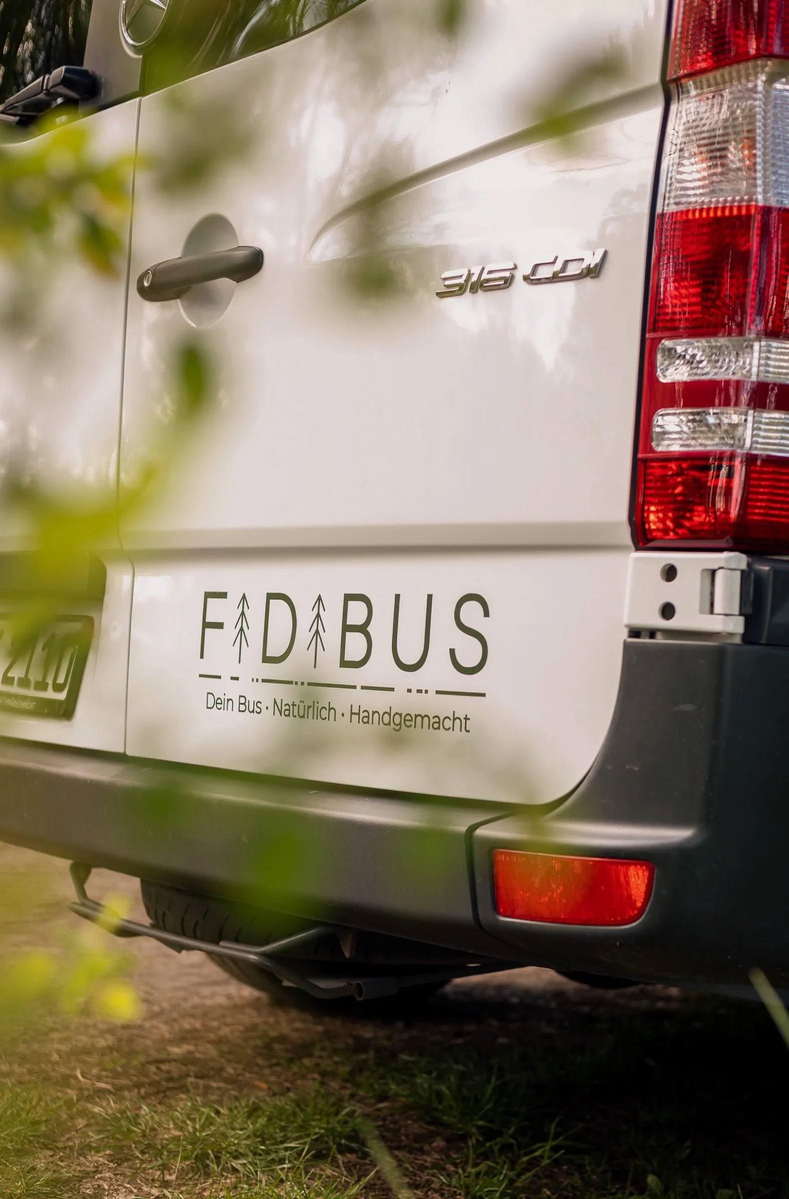 FidiBus Campervan mit geöffneten Hecktüren im Grünen